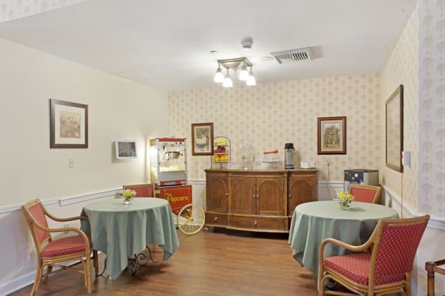 A cozy indoor room with tables and chairs, featuring a popcorn machine and decorative framed pictures on the walls.