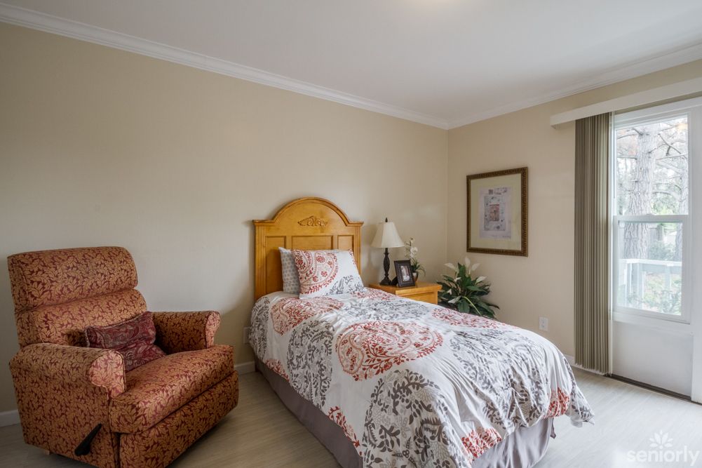 A cozy bedroom with a single bed, patterned quilt, and an armchair.