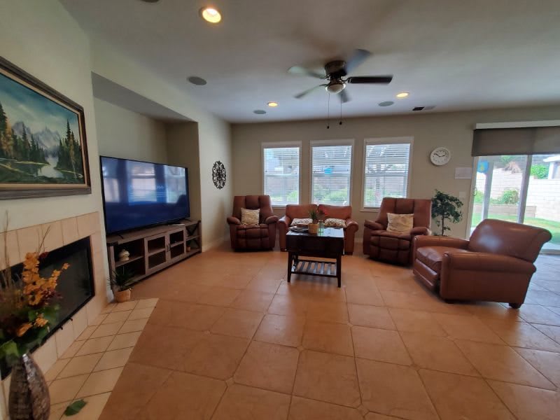 A cozy living room with a large TV, several sofas, and a coffee table on a tile floor.