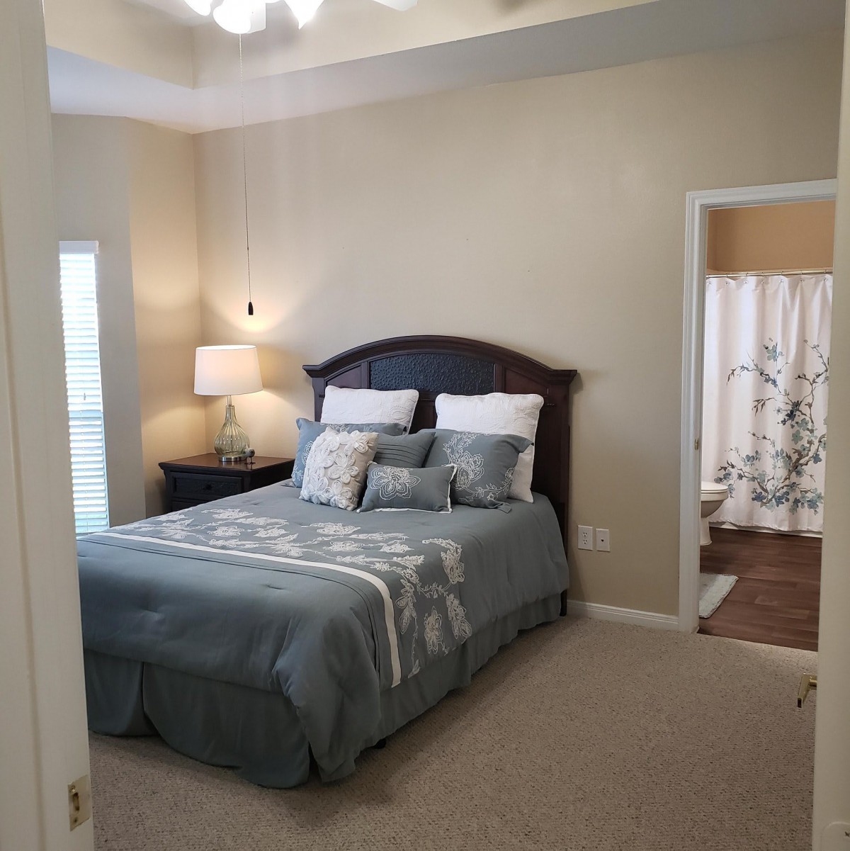 A cozy bedroom featuring a neatly made bed, soft pillows, and a bedside lamp.
