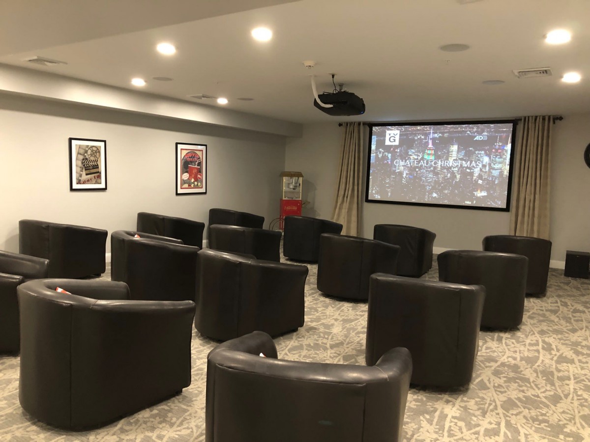 A cozy home theater setup with multiple chairs facing a large projector screen.