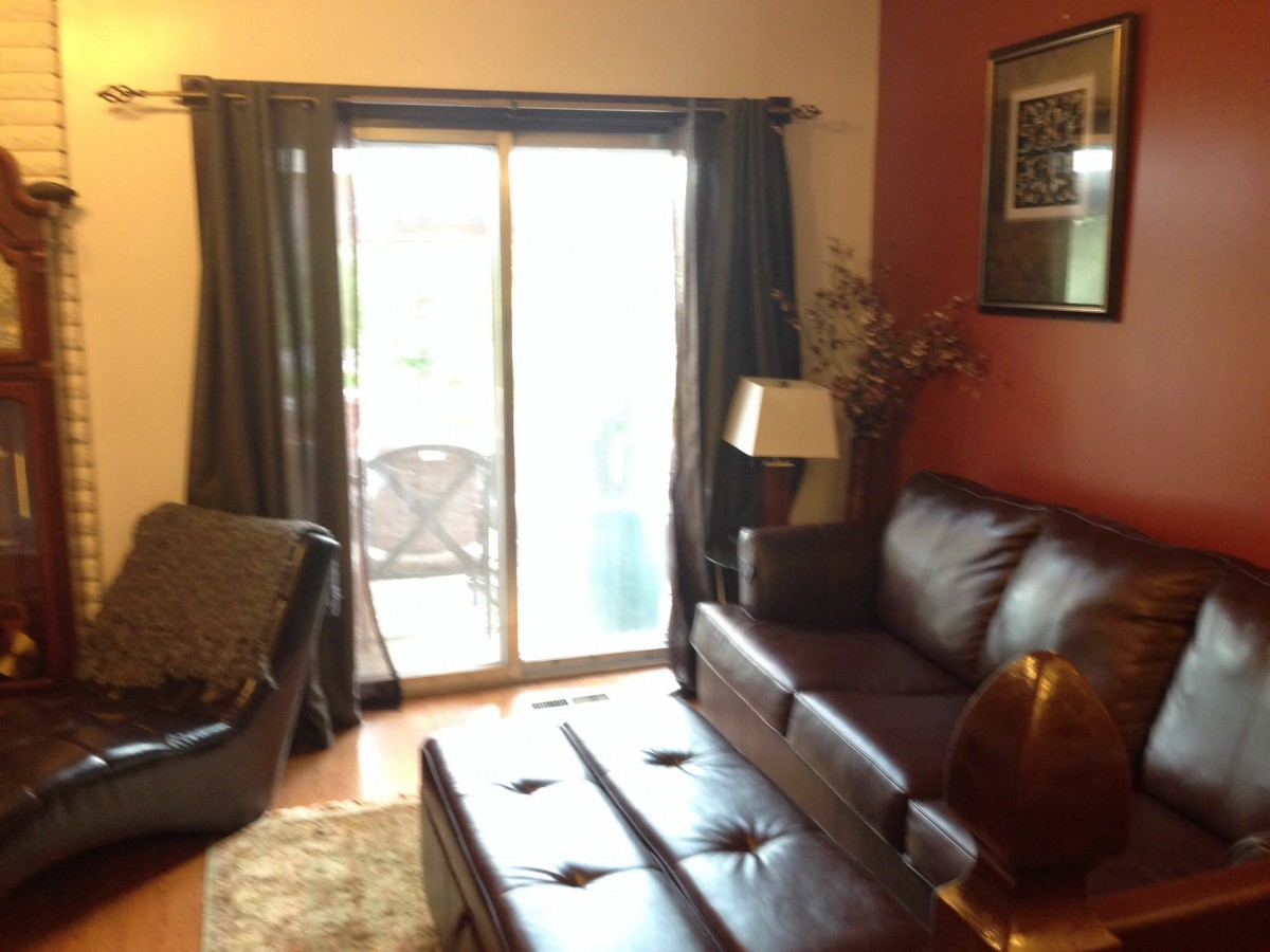 A cozy living room with a leather sofa, coffee table, and sliding glass doors leading to a patio.