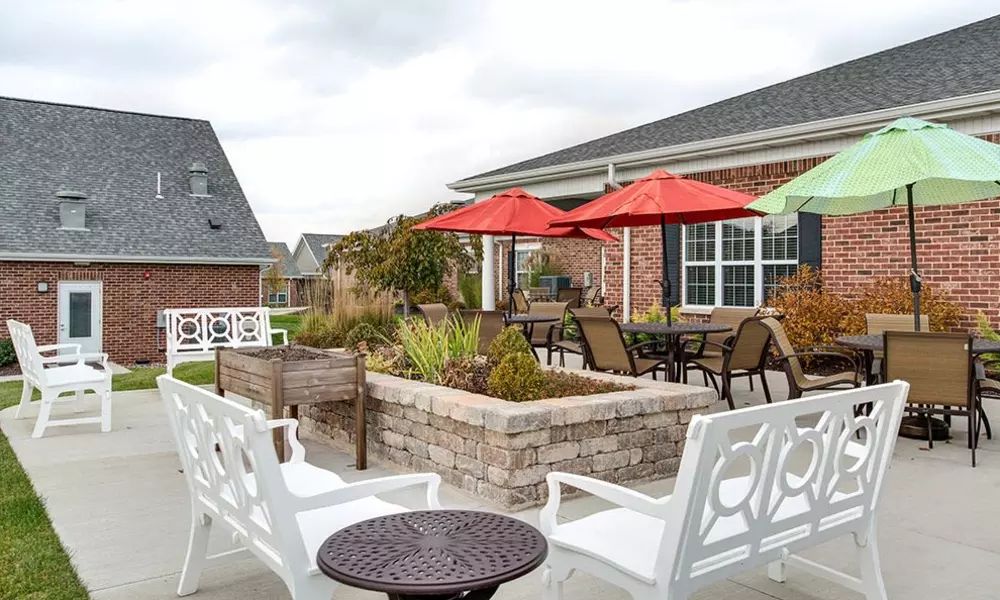 A cozy patio area with tables, chairs, and bright umbrellas under a cloudy sky.