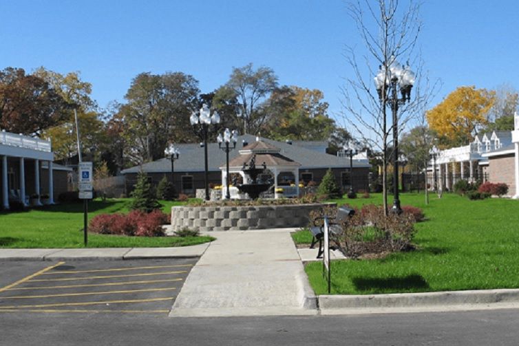 A scenic view of a building surrounded by landscaped greenery and lamp posts on a sunny day.