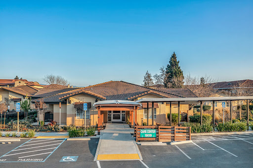 A modern commercial building with a welcoming entrance and landscaped surroundings under a clear blue sky.