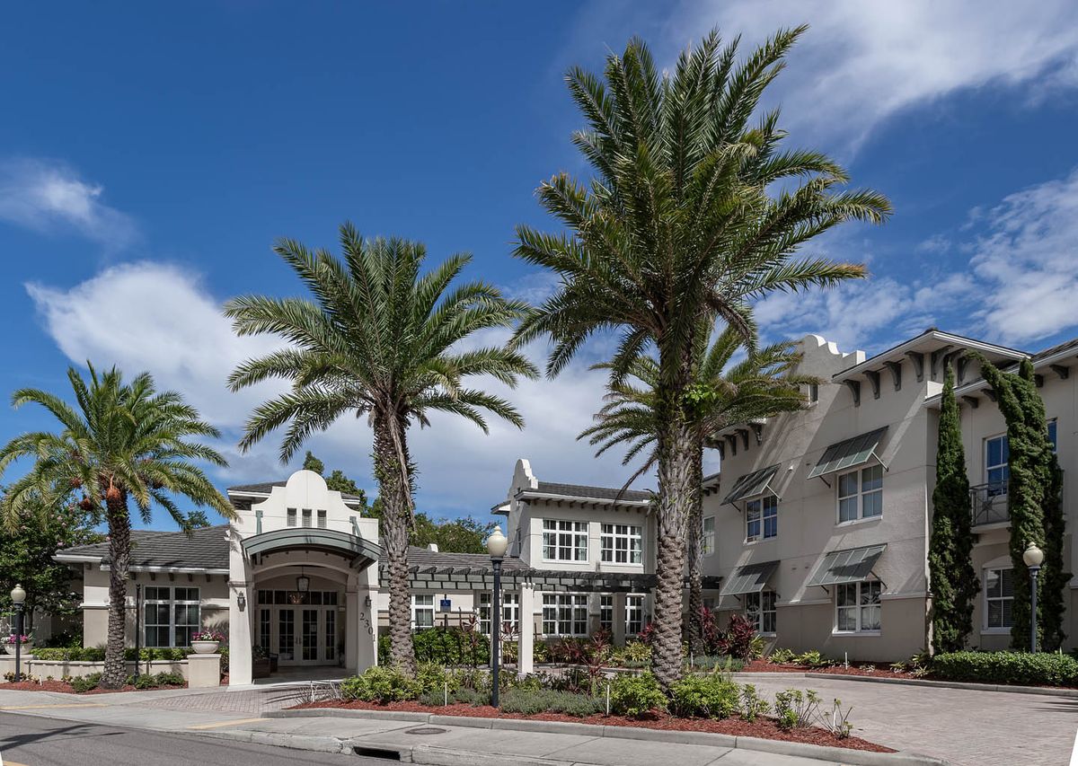 A building with palm trees and a blue sky backdrop.