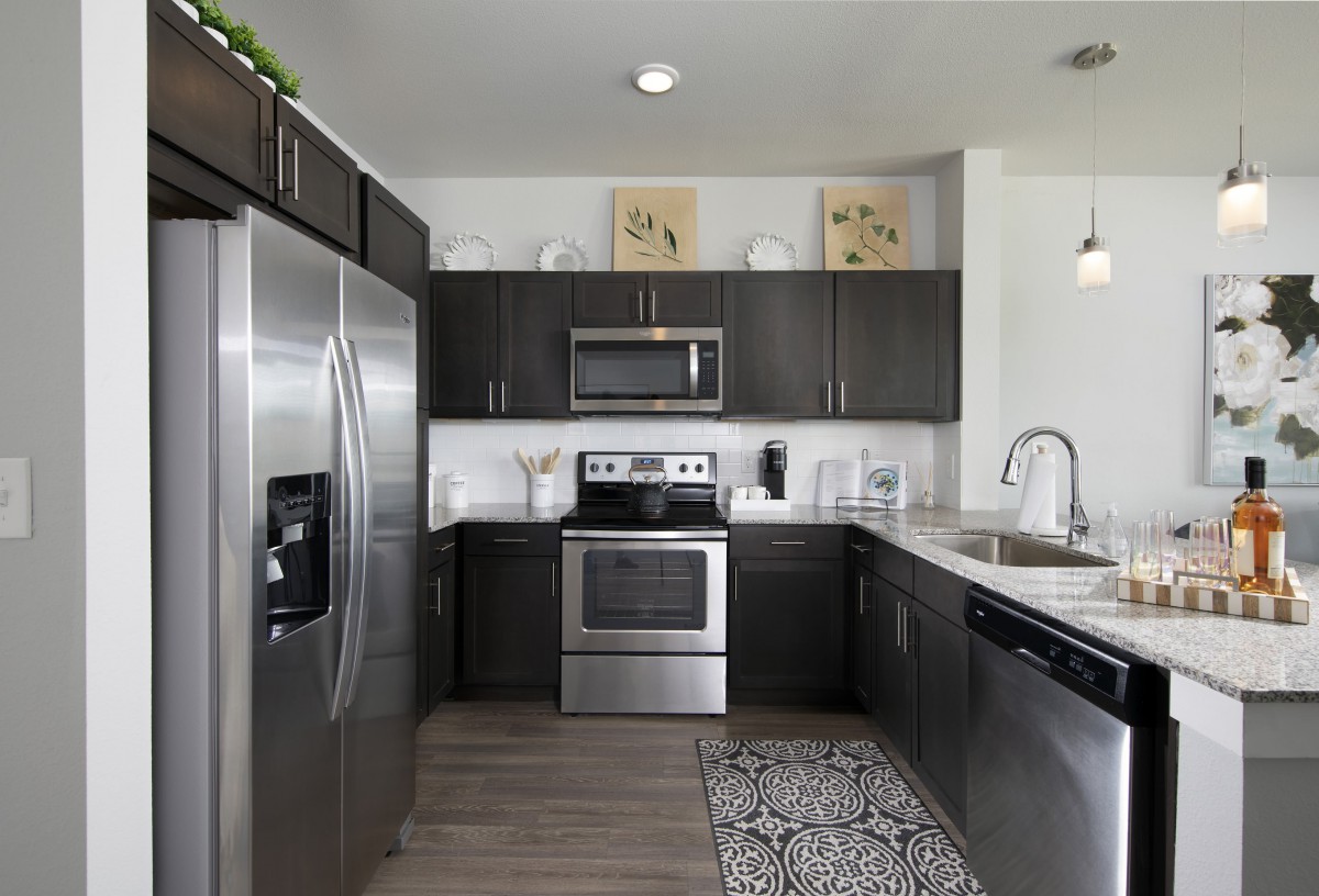 A modern kitchen with stainless steel appliances and dark cabinets.