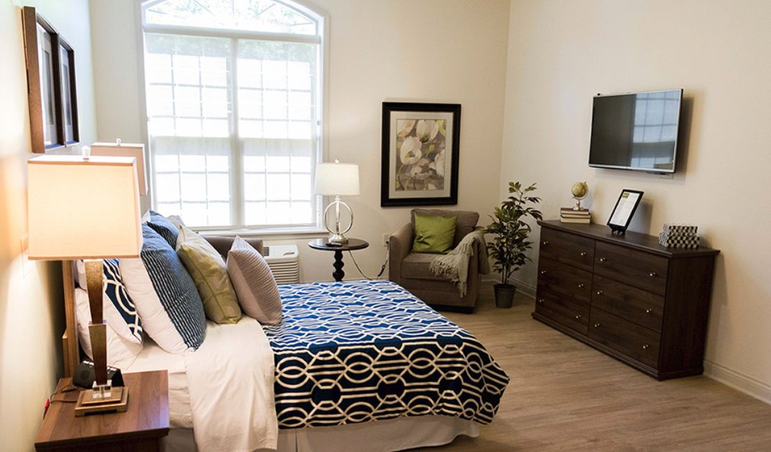 A cozy and well-decorated bedroom with a modern interior design, featuring a comfortable bed, armchair, dresser, and decorative elements.