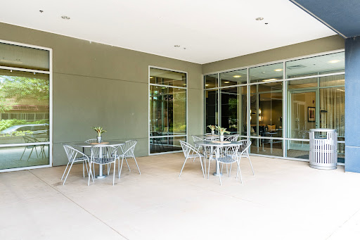 A modern outdoor patio area featuring glass walls and stylish furniture.