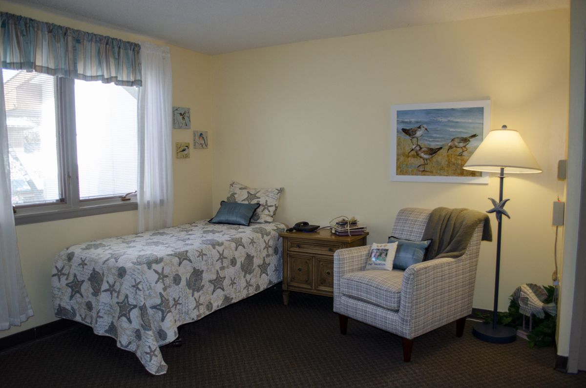 A cozy bedroom with a single bed, armchair, and decorative elements.