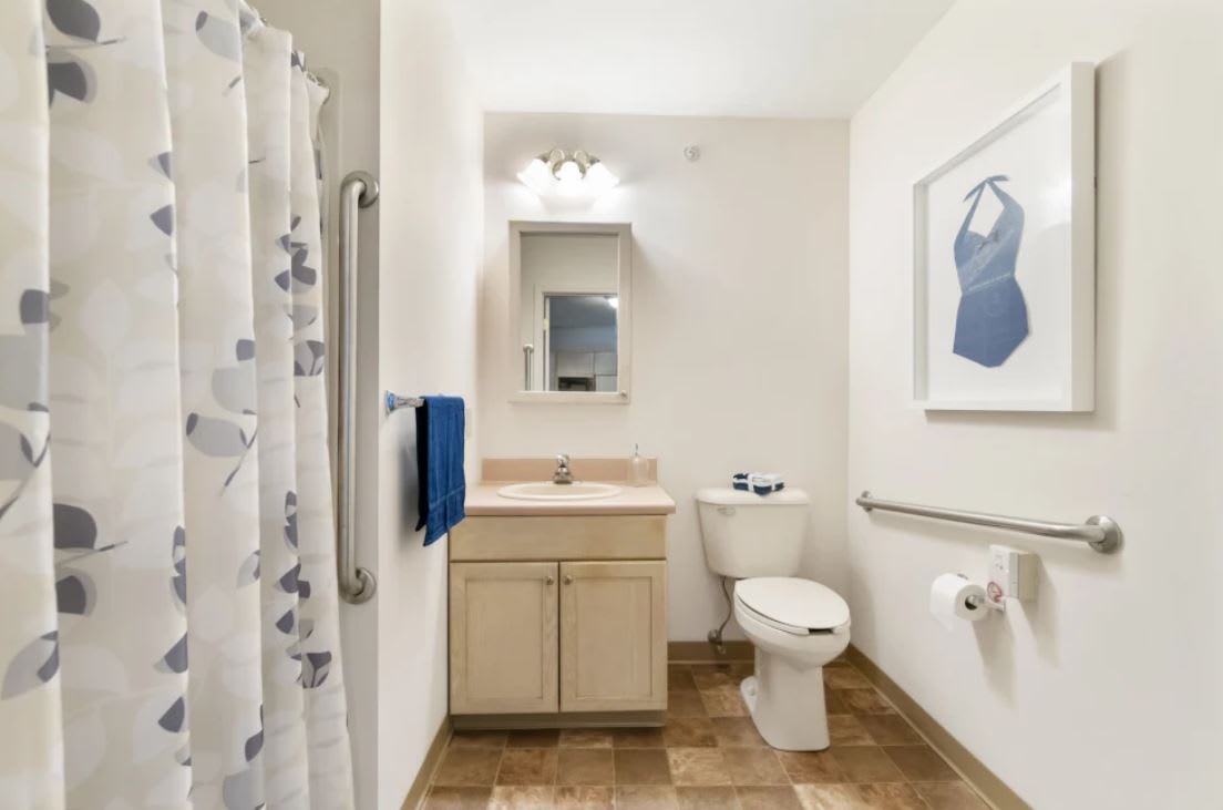 A clean and well-lit bathroom with a toilet, sink, and shower.