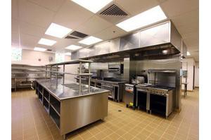 Industrial kitchen setup with stainless steel appliances and workstations.