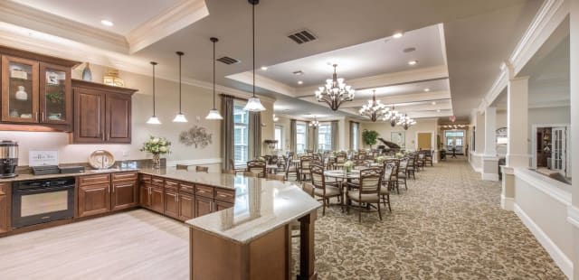 A spacious dining room with elegant chandeliers and neatly arranged tables and chairs.