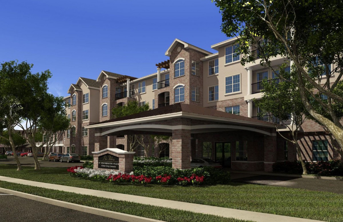 A modern residential apartment building with well-maintained landscaping under a clear blue sky.