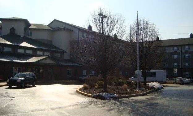 A building with a driveway and trees on a sunny day.