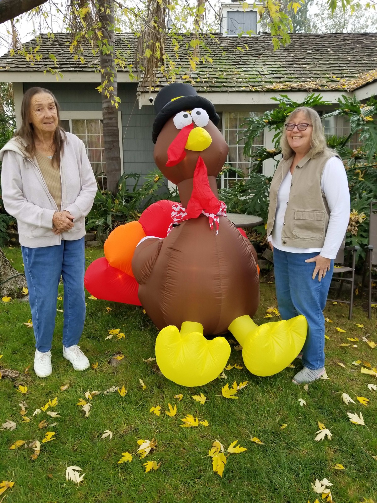 Two people standing next to a large inflatable turkey decoration.