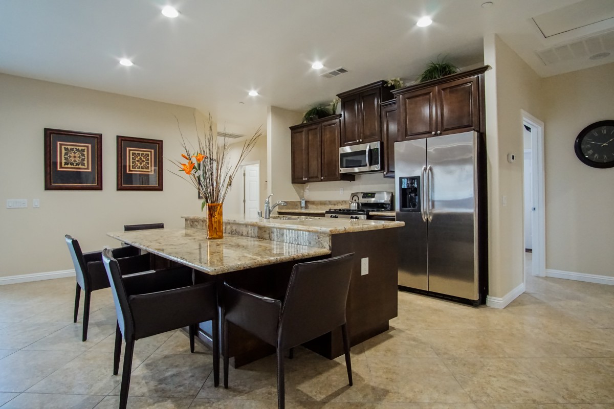 A modern kitchen with a dining area, featuring stainless steel appliances and a stylish countertop adorned with a vase of flowers.