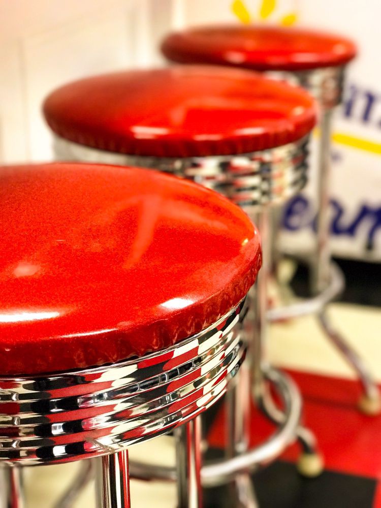 Retro red and chrome diner stools lined up.
