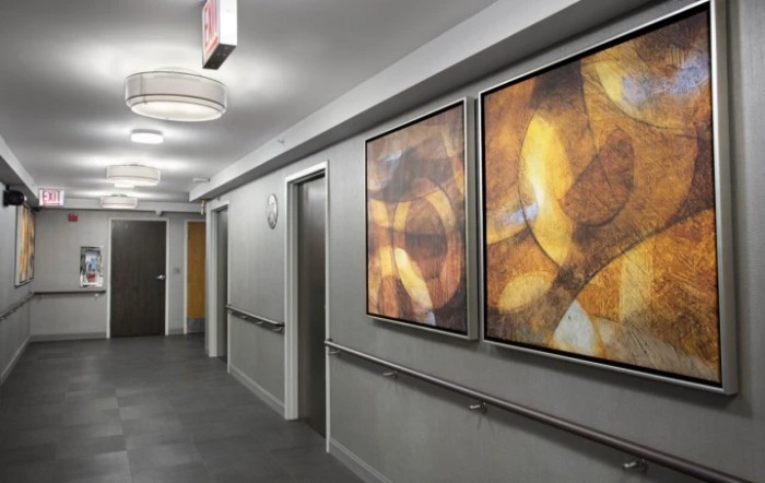 A modern hallway featuring abstract paintings and ceiling lights.