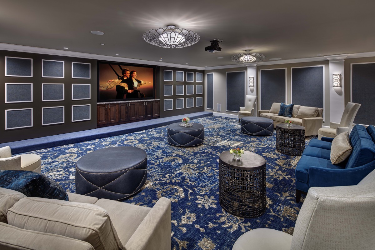 A luxurious theater room featuring comfortable seating and a large projector screen with a modern blue color scheme.