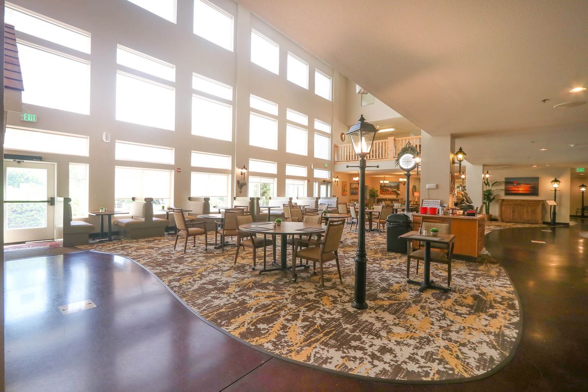 A spacious and brightly lit dining area with large windows, tables, and chairs.