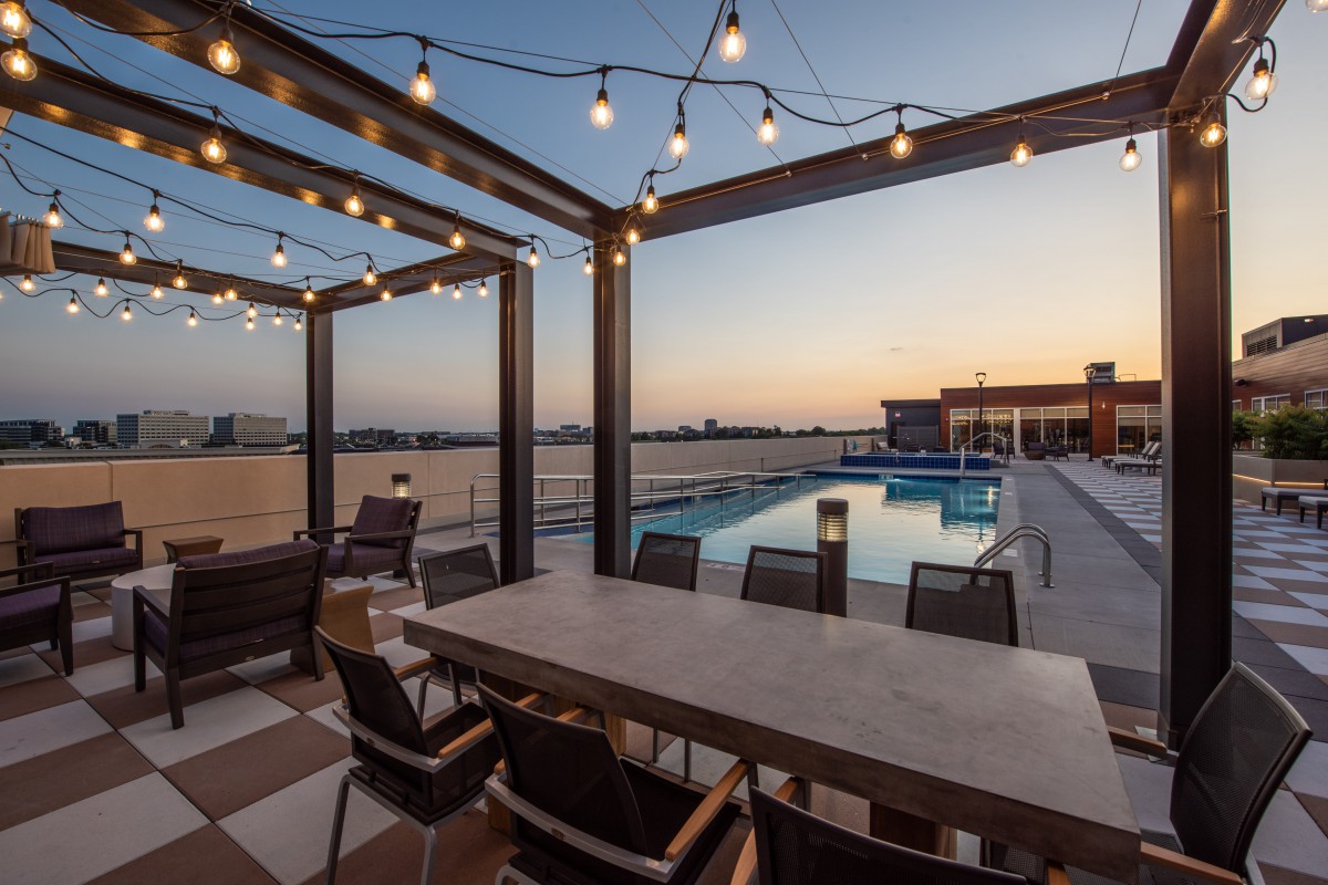 A cozy outdoor patio with string lights overlooking a pool at sunset.