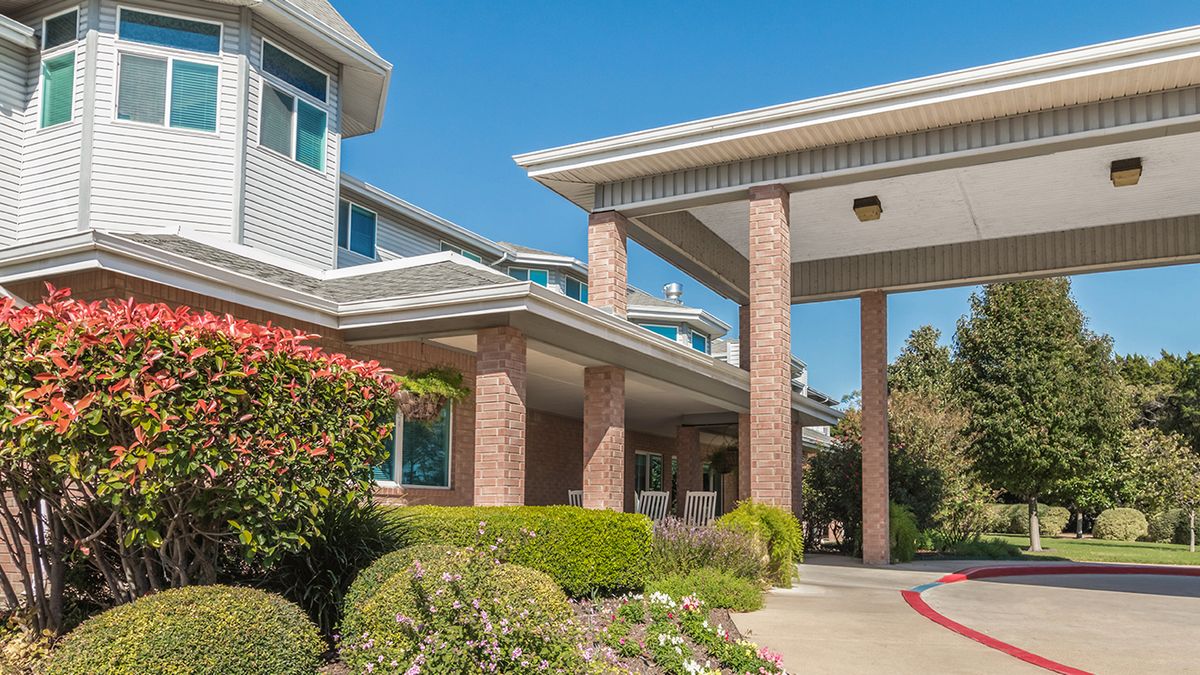 A view of a modern residential building entrance with well-maintained landscaping.