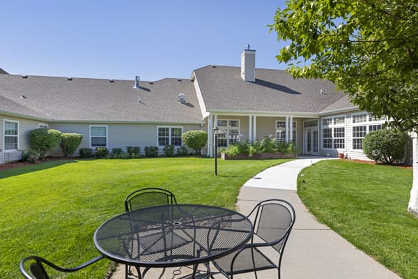A peaceful backyard view with a table and chairs on a sunny day.