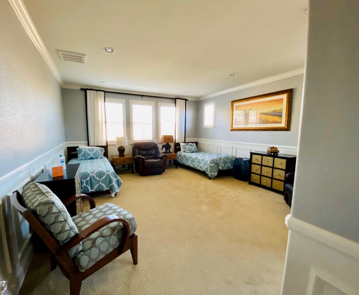 A spacious bedroom with two twin beds, armchairs, and ample natural light.
