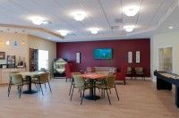A spacious lounge area with tables, chairs, and a TV on the wall.