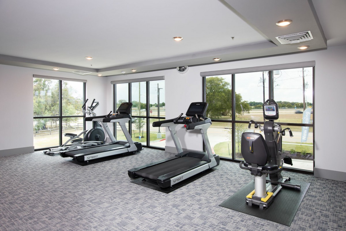 A modern gym with various exercise equipment including treadmills and stationary bikes.