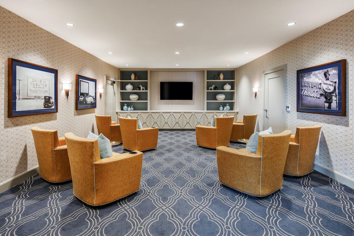 A modern lounge area with comfortable seating and a television, featuring decorative shelving on the walls.
