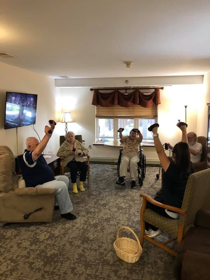 A group of elderly individuals participating in an indoor exercise session.