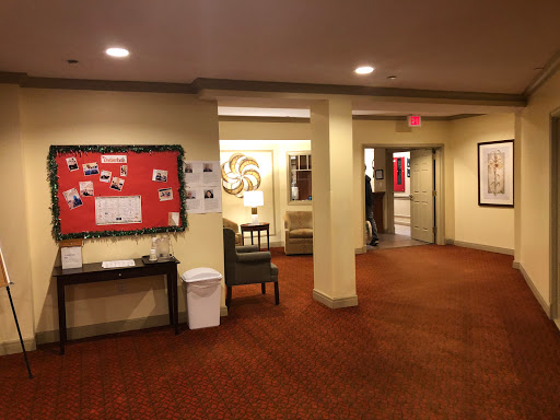 A view of a well-lit hallway with a community bulletin board and seating area.