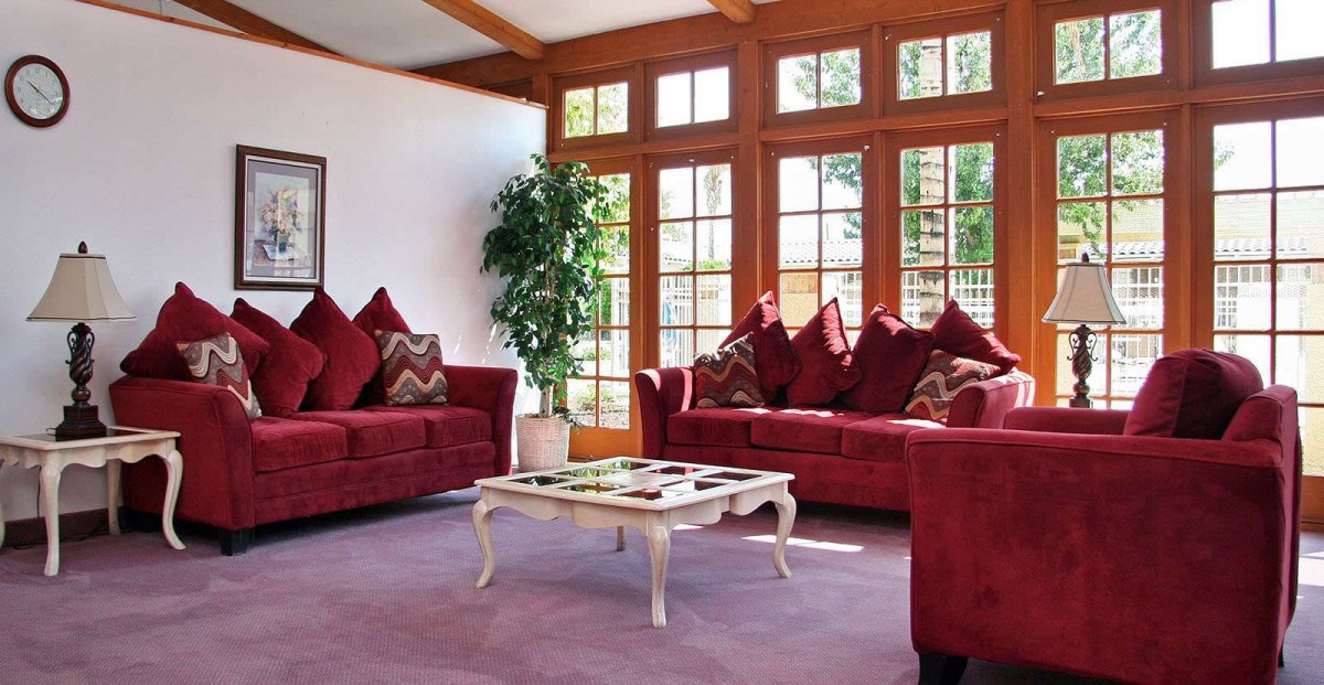 A cozy living room featuring red sofas and a white coffee table, with large windows allowing natural light to fill the space.