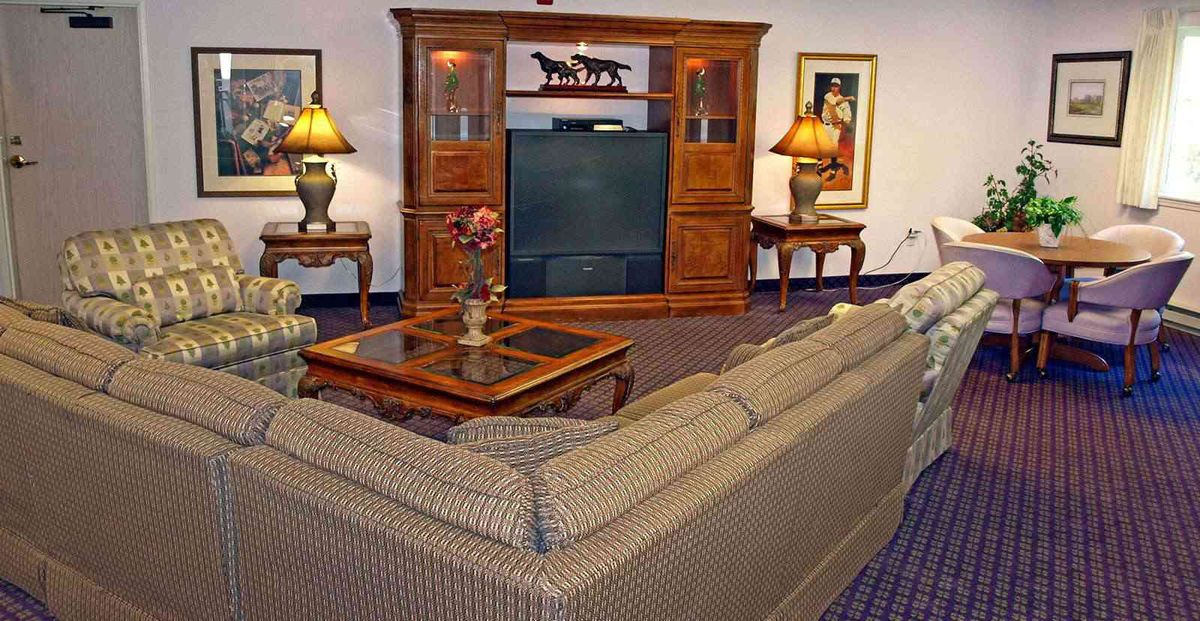 A cozy living room featuring a large sofa, an entertainment center with a television, lamps, and decorative elements.