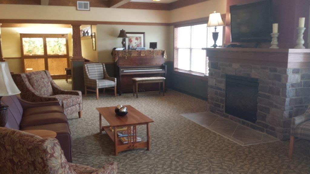 A cozy living room with a piano, fireplace, and comfortable seating.