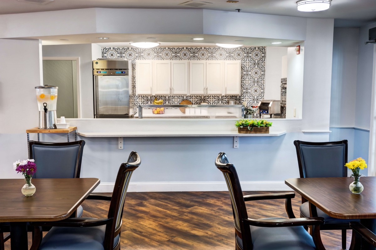 A modern kitchen with a dining area featuring a clean and stylish design, equipped with appliances and dark wood furniture.