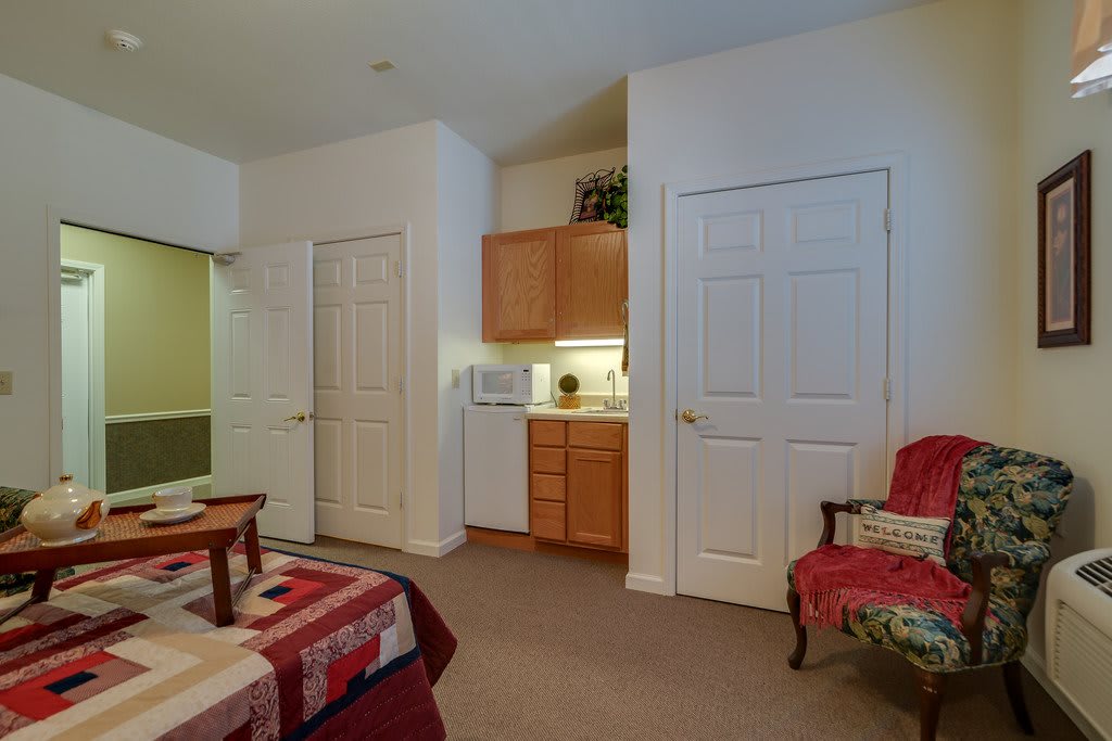 A cozy bedroom with a bed, chair, and built-in wardrobes.