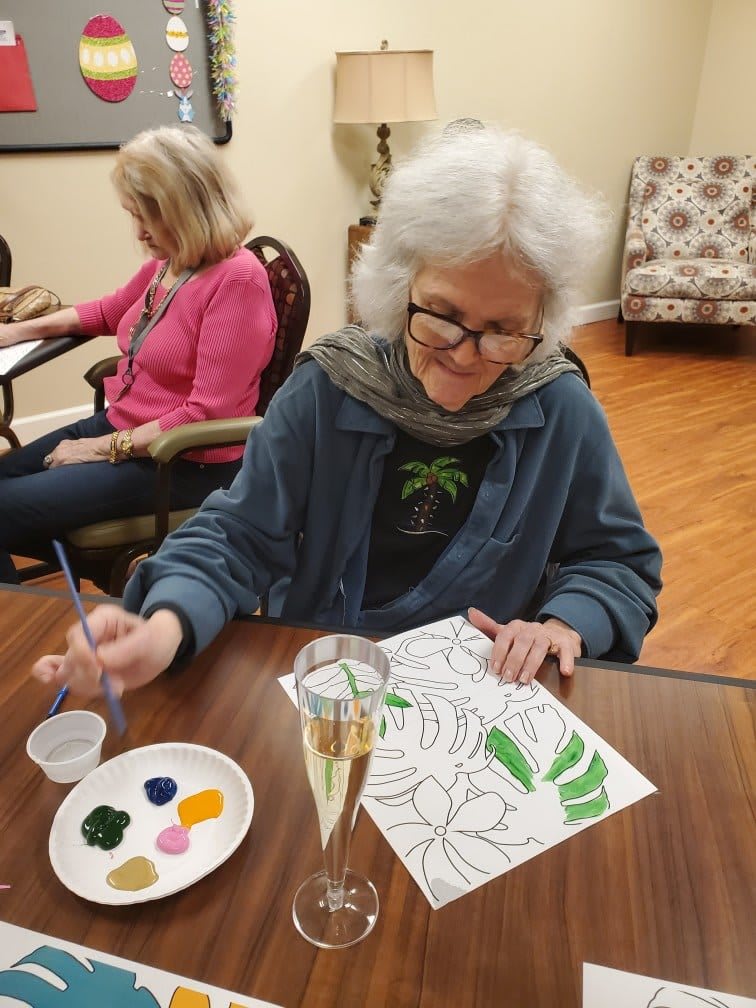 An elderly woman engaged in painting as a creative hobby indoors.