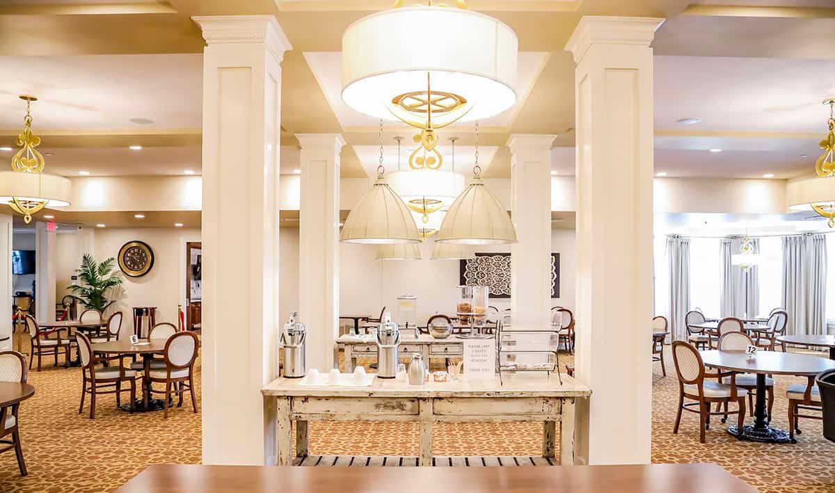 An elegantly decorated restaurant dining area with chandeliers and neatly arranged tables and chairs.