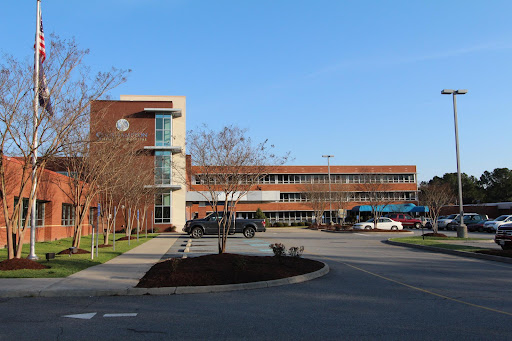 A modern architectural building with a parking lot, captured on a clear day.