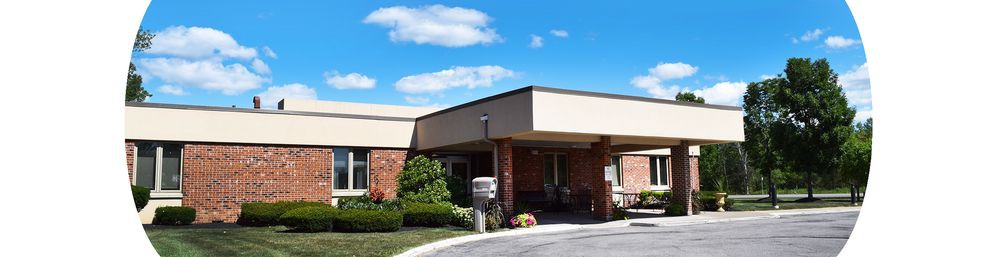 A modern building entrance under a clear blue sky with landscaped surroundings.