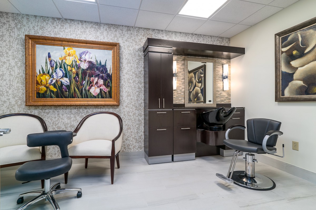 A modern salon interior with stylish chairs, a mirror, and colorful artwork on the wall.