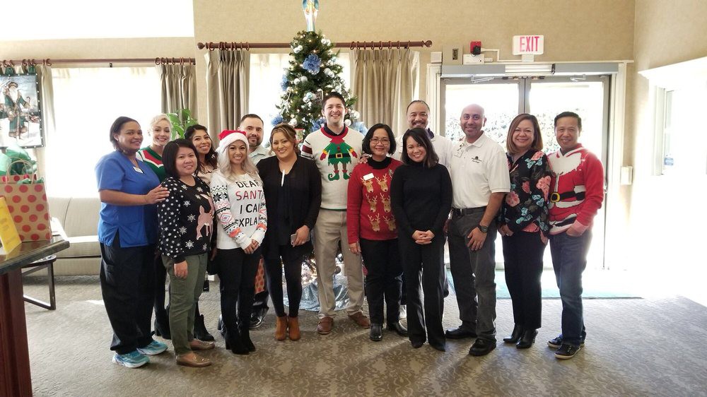 A group of people posing in festive clothing in front of a decorated Christmas tree indoors.