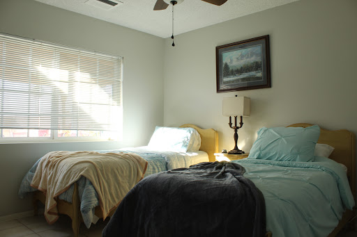 A cozy and inviting bedroom featuring two beds, a lamp, and a serene painting on the wall.