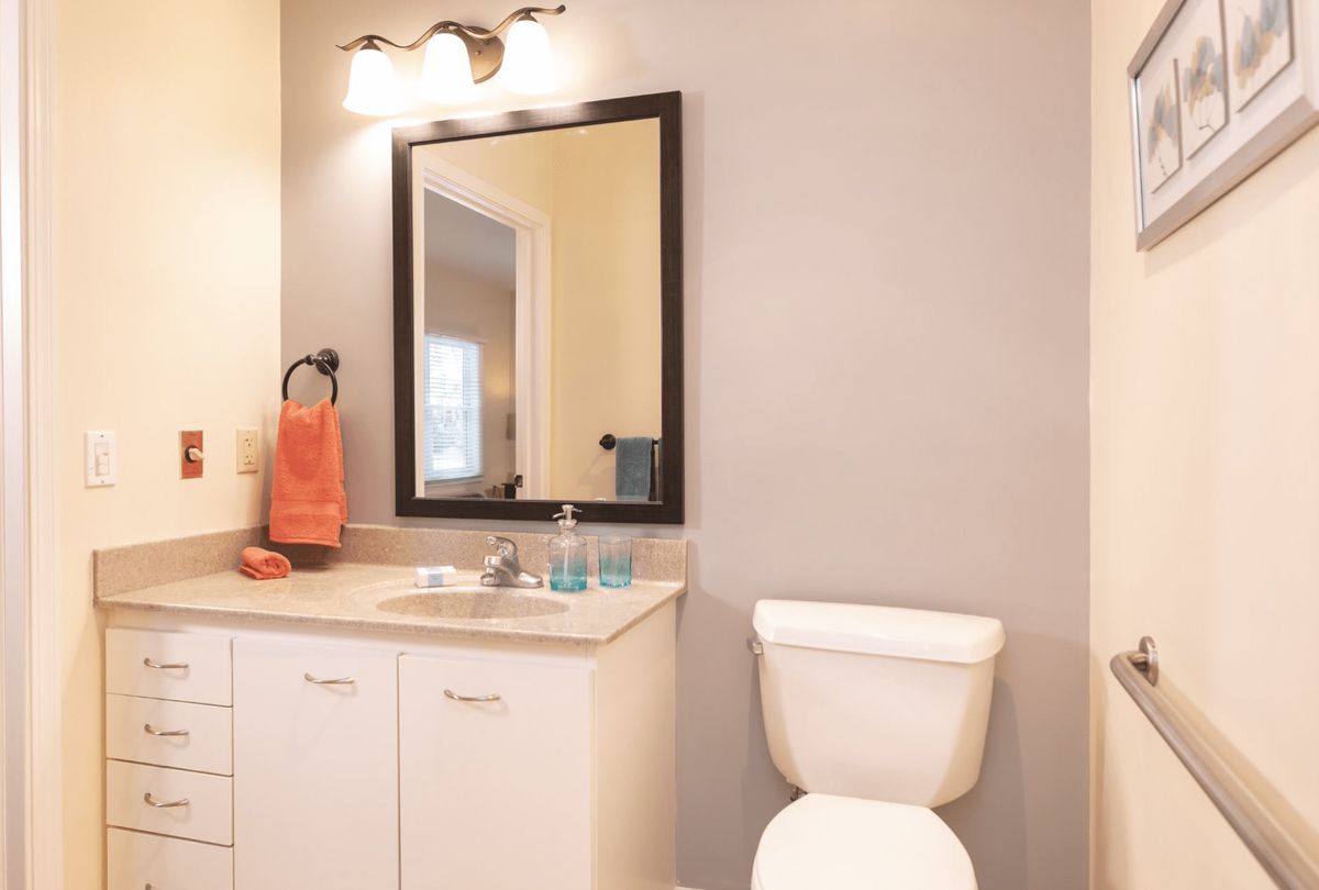 A modern bathroom with a sink, mirror, and toilet.