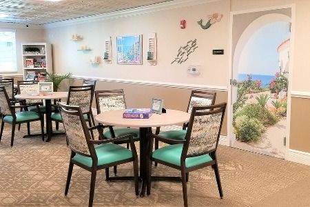 A cozy indoor seating area with a round table and four chairs, decorated with wall art and a calming atmosphere.