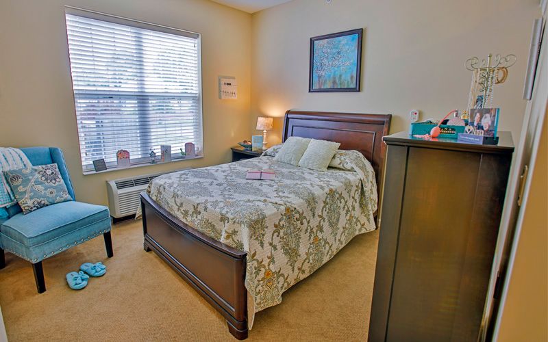 A cozy bedroom with a neatly made bed, wooden furniture, and soft lighting.
