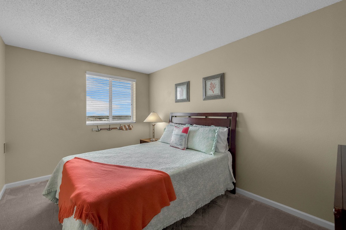 A cozy bedroom with a neatly made bed, featuring soft colors and natural light coming through the window.